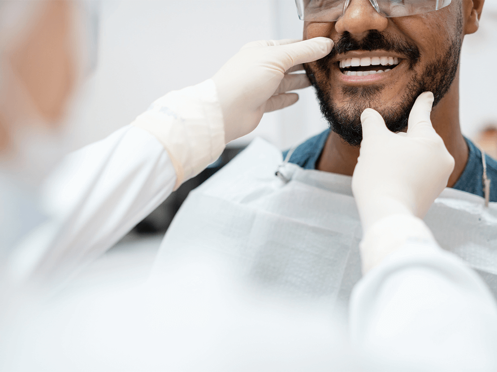 a dentist wearing gloves examining a man