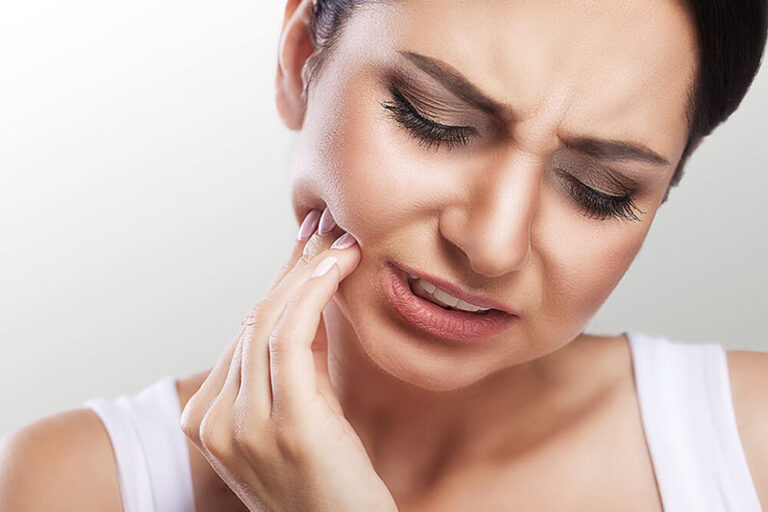 woman with a dental emergency applying pressure to jaw